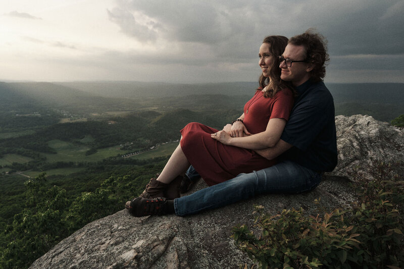 Couple cuddles together on top of a mountain