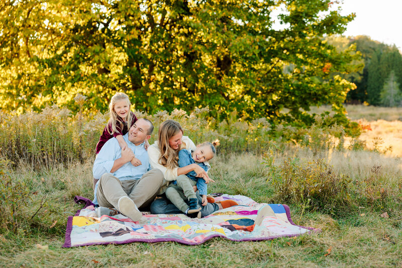 The McCoy family enjoying a beautiful night sitting on a picnic blanket at The Higlands Park in Grand Rapids, MI during the sunset