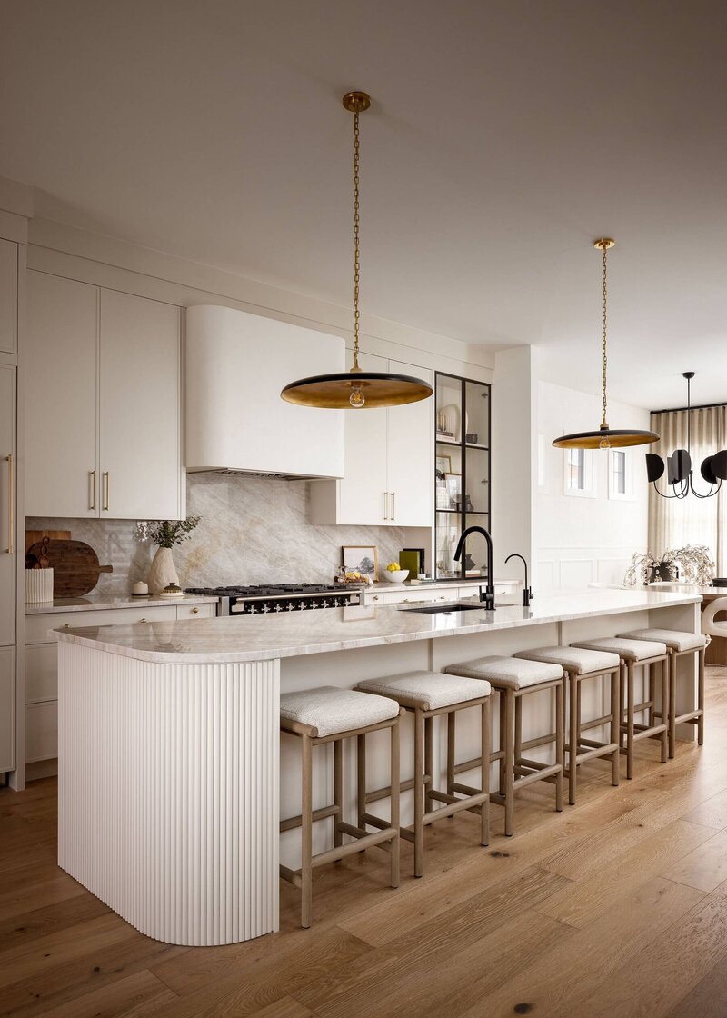 Oversized island with taj mahal quartzite with pendant lighting and fluted details. 