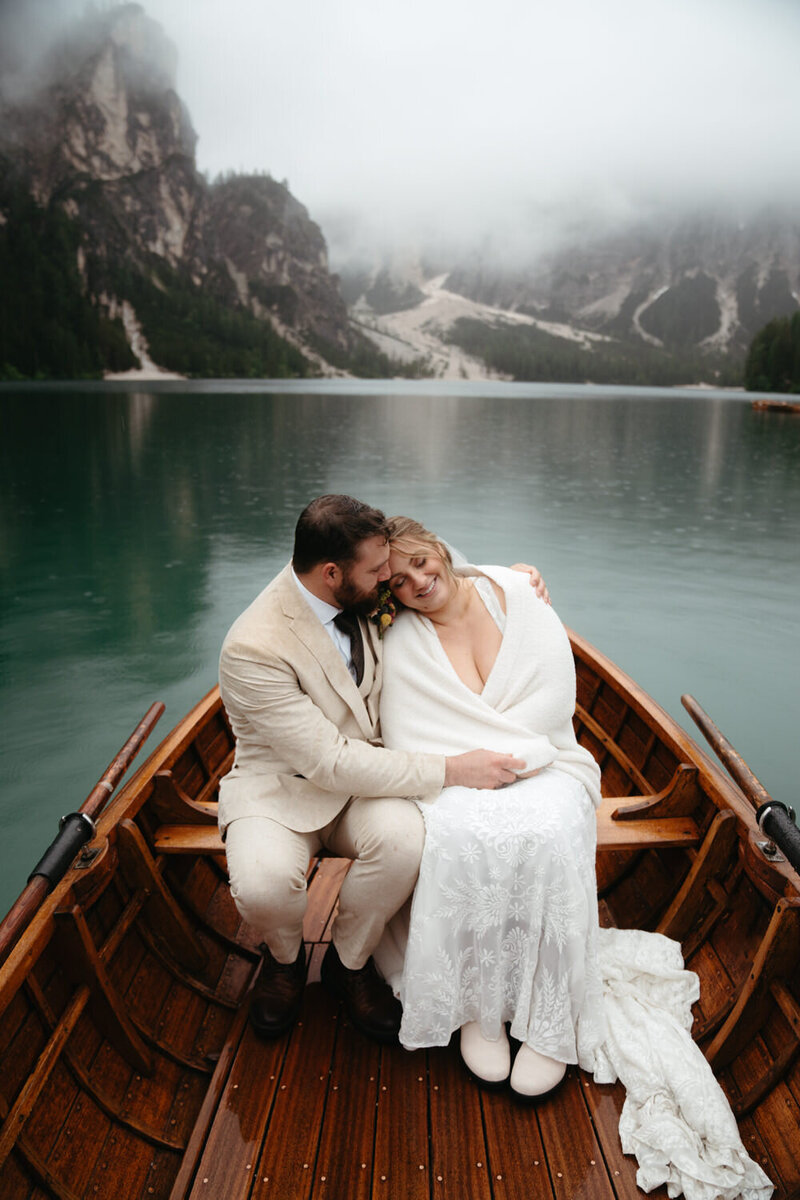 Bride smiles big as her Groom embraces her on a rowboat during their Dolomites Elopement 