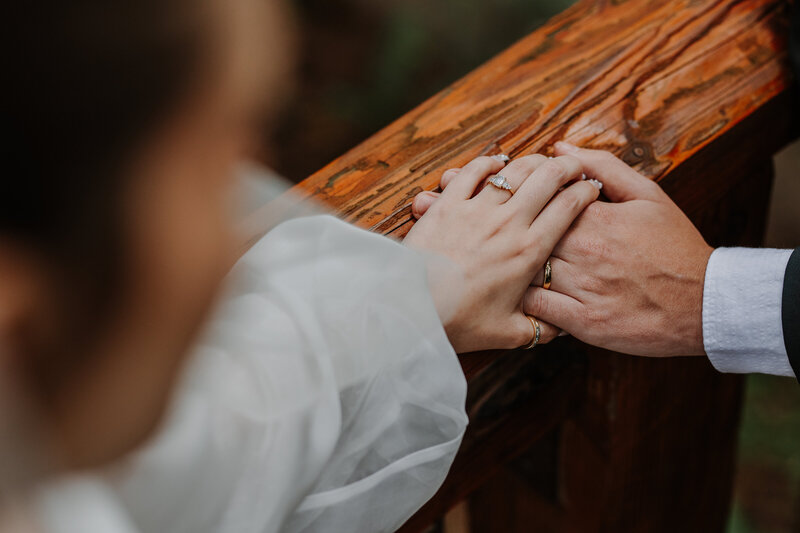 Bride and groom holding hands on wood railing