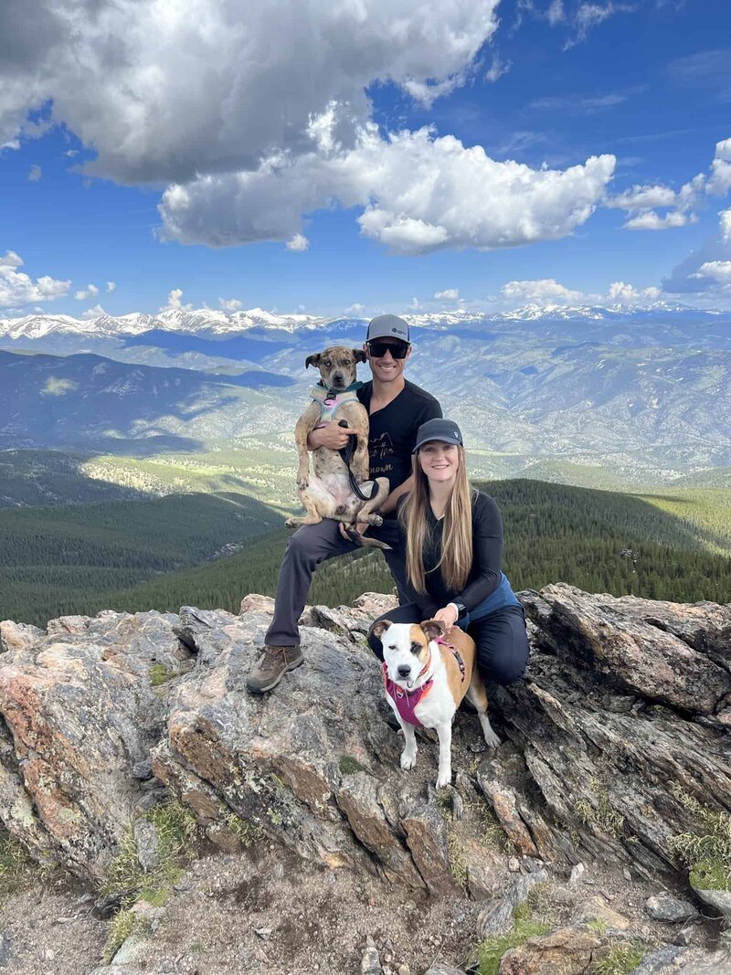 Devon Denys enjoying a serene mountain hike with her dogs, embodying the spirit of wellness and outdoor living in Colorado.