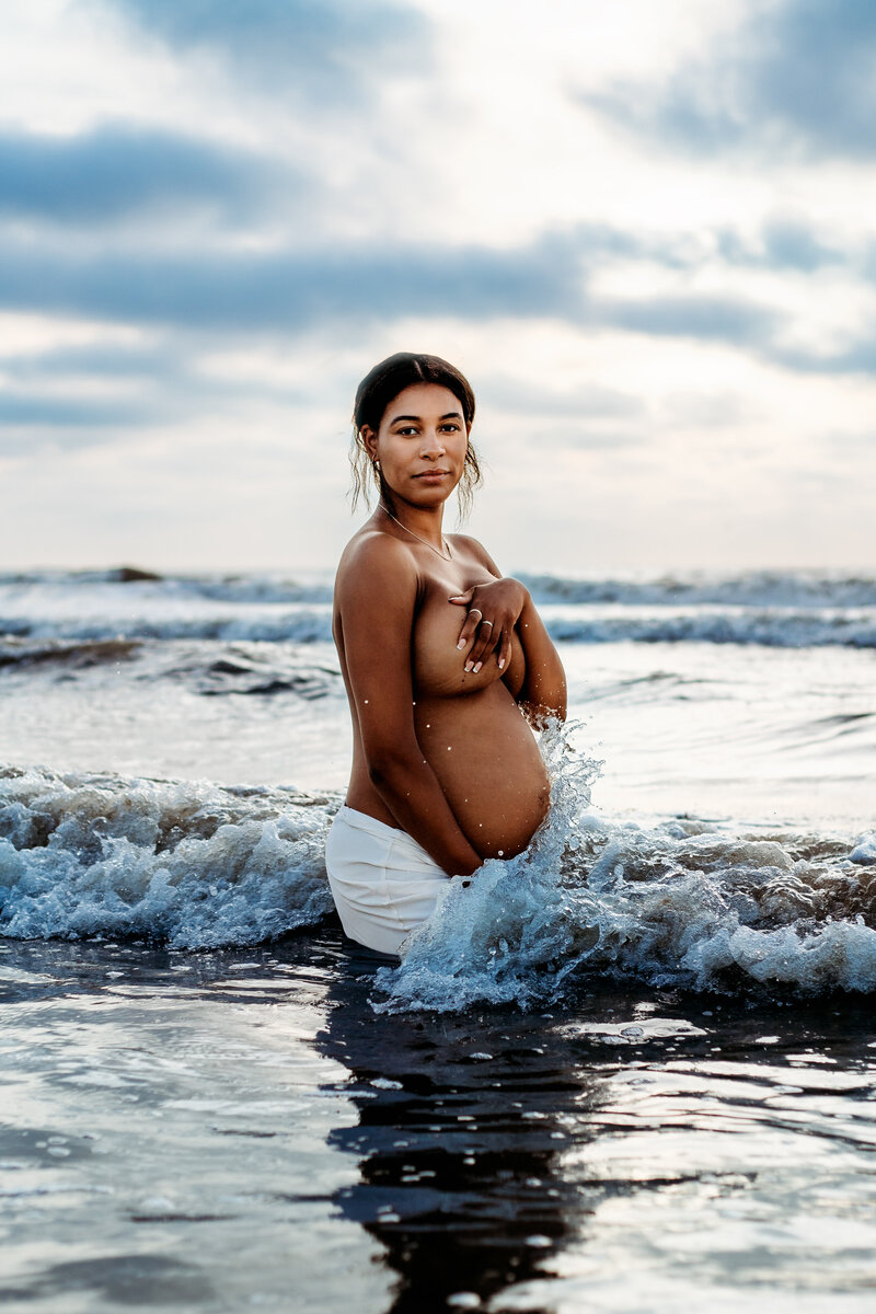 zwangere vrouw in zee tijdens fotoshoot zwangerschap