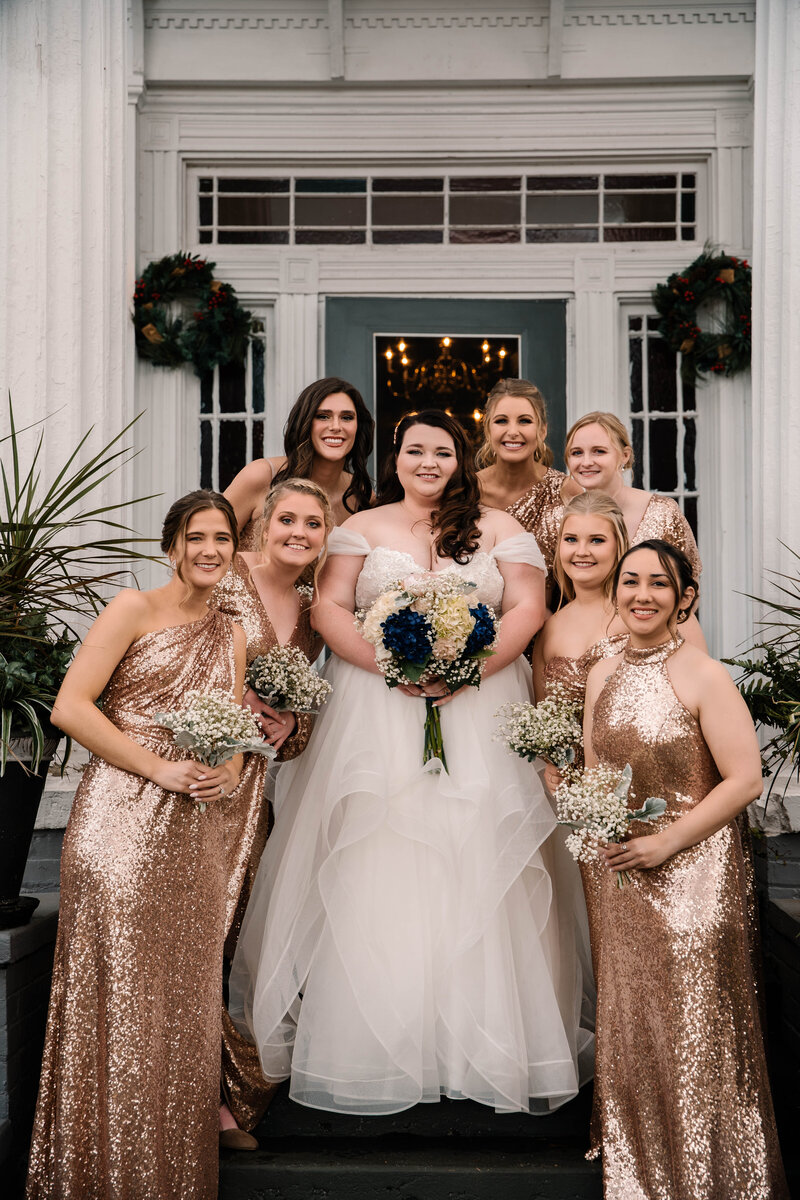 Bride and her bridesmaids smile while stacked on the stars at Englund Estate Wedding Venue.