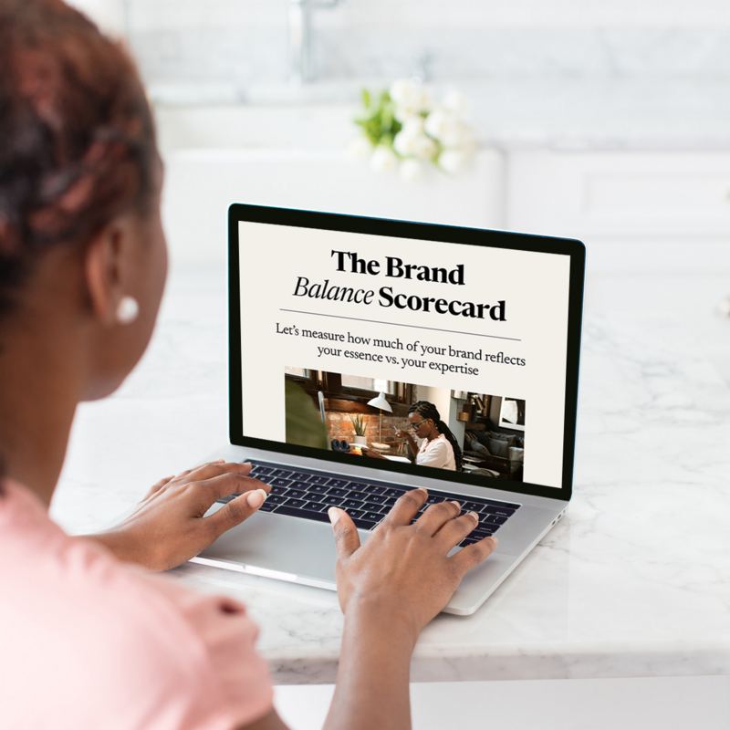 Black woman looking at laptop in a well lit kitchen