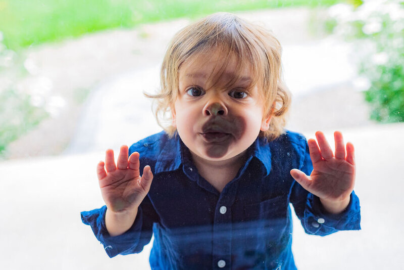 A kid smooshes their face against glass.
