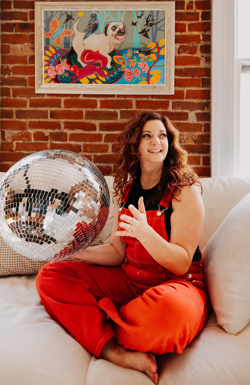 A woman sitting on a couch holding a disco ball.