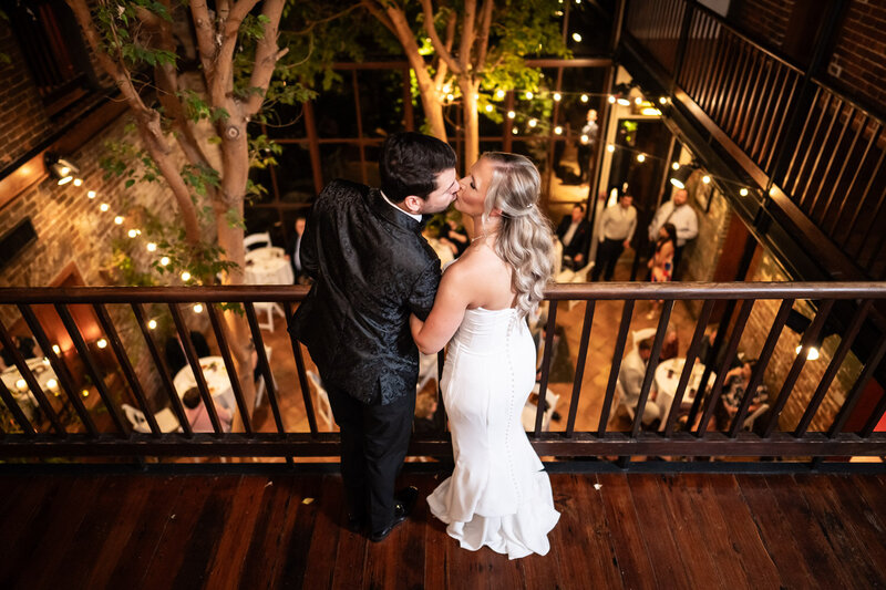Bride and groom kiss on balcony of Rosy's Jazz Hall in New Orleans