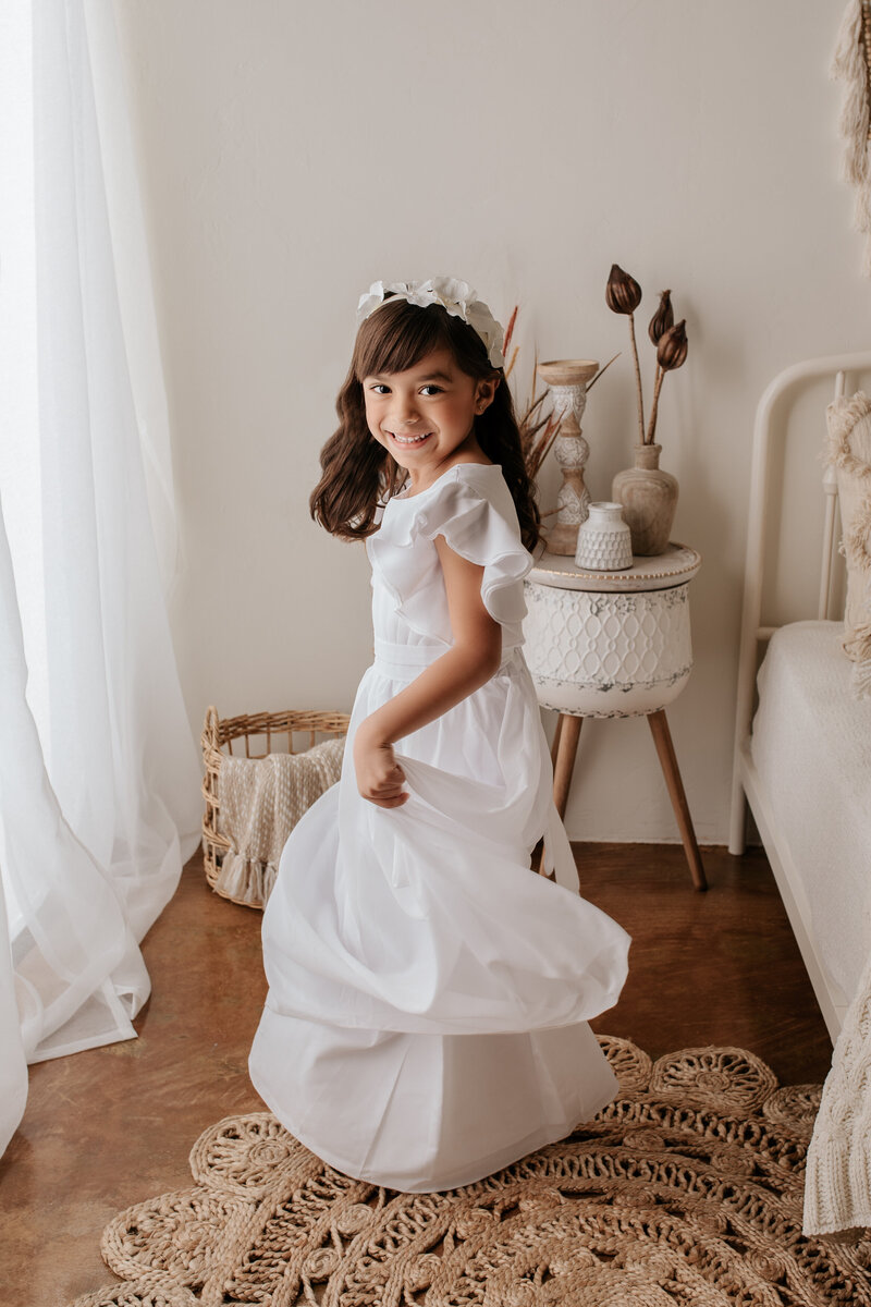 young girl twirling in a white dress during her photography session in a Tucson studio