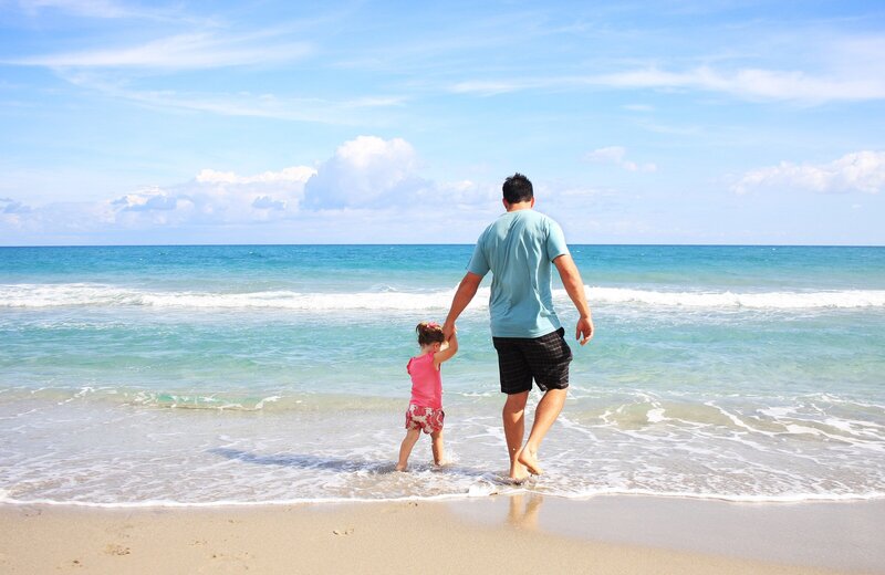 father son holding hands at beach