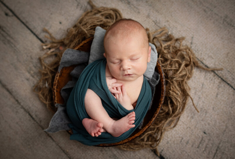 Newborn baby boy wrapped with feet and hands sticking out cutely