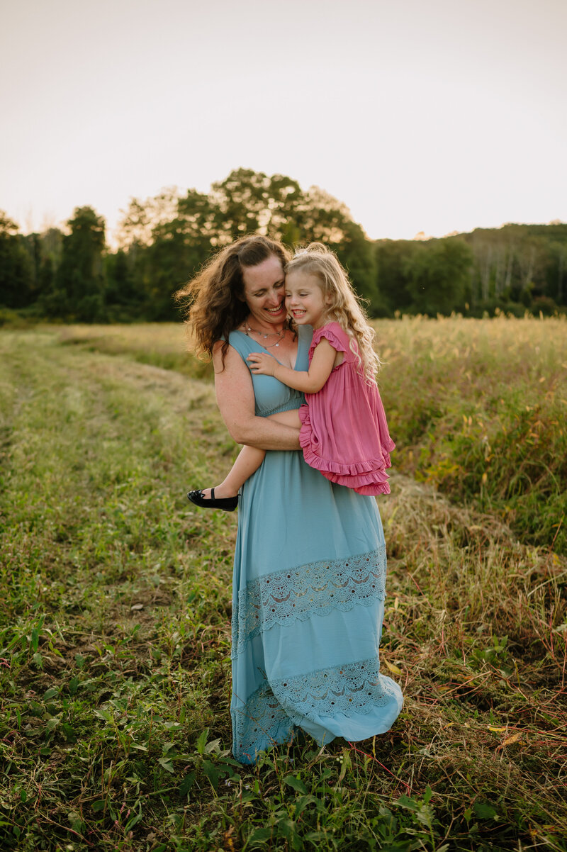 woman and girl wearing long flowy dresses dancing in a field