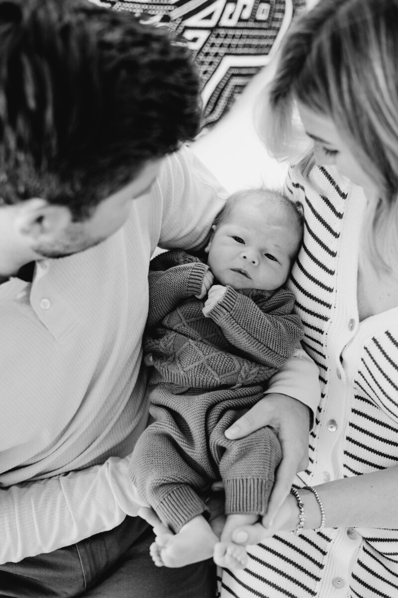 New parents lovingly holding newborn baby, intimate in-home Wilmington newborn photography