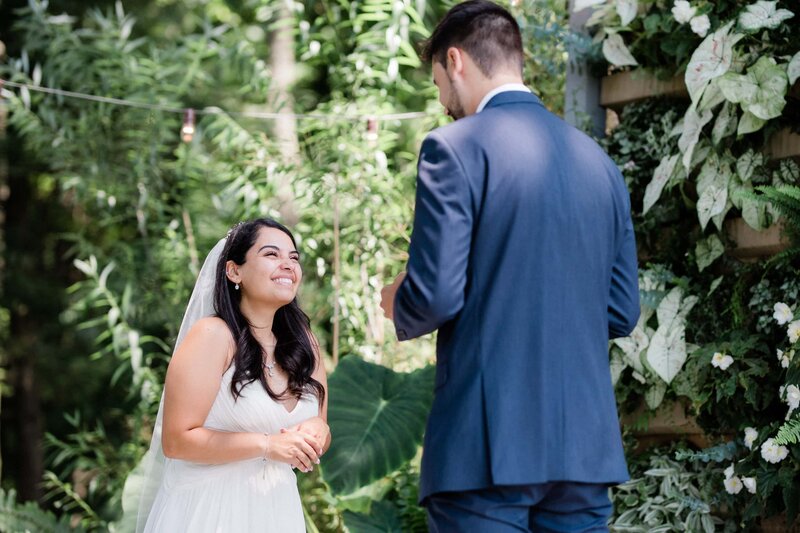 true to color photo of bride smiling while groom reads his vows