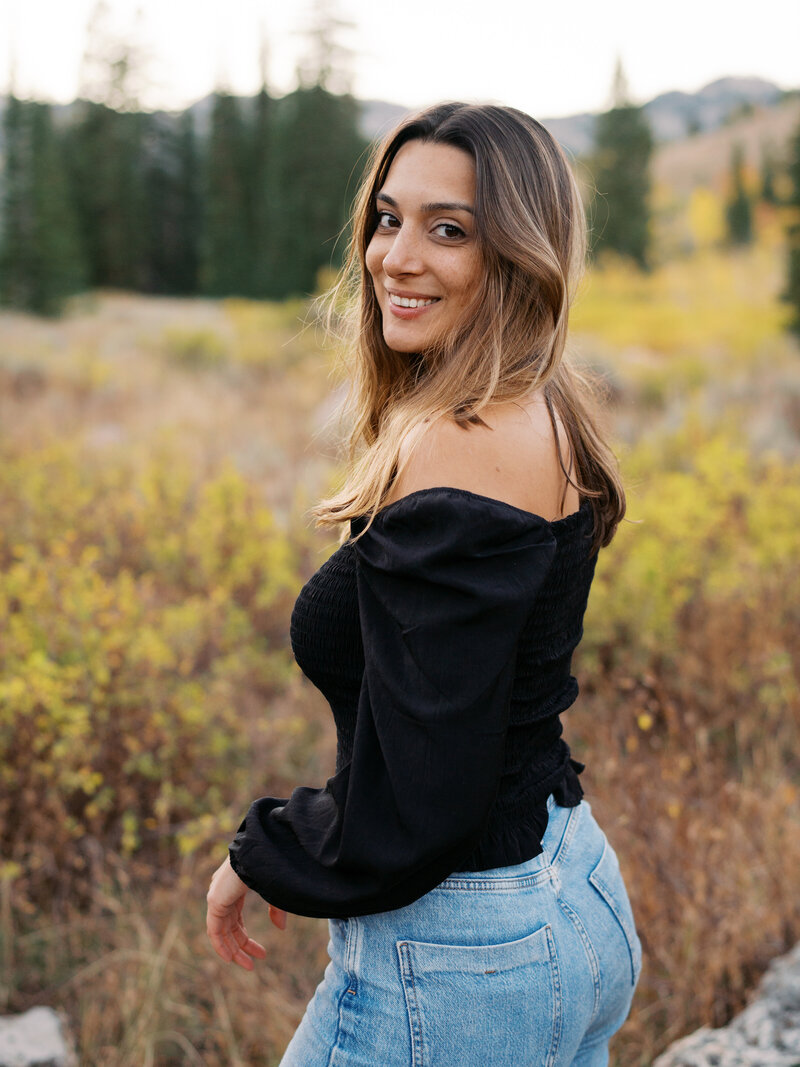 Couple in field, looking down at pregnant mom's belly