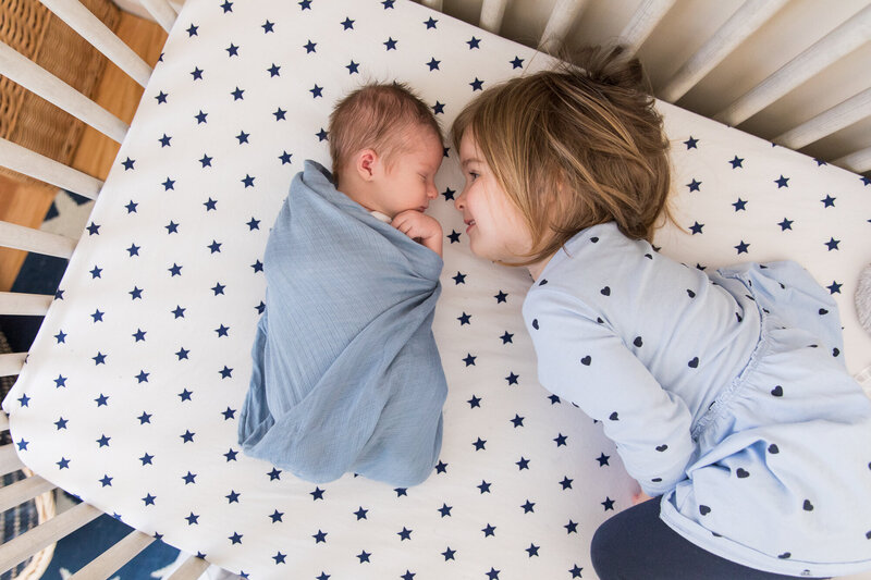 Sleeping newborn and toddler together in crib