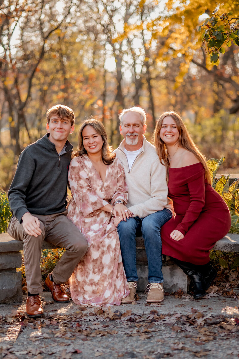 A gorgeous family of four sitting on a stone bench at Bee Tree park in St.Louis.