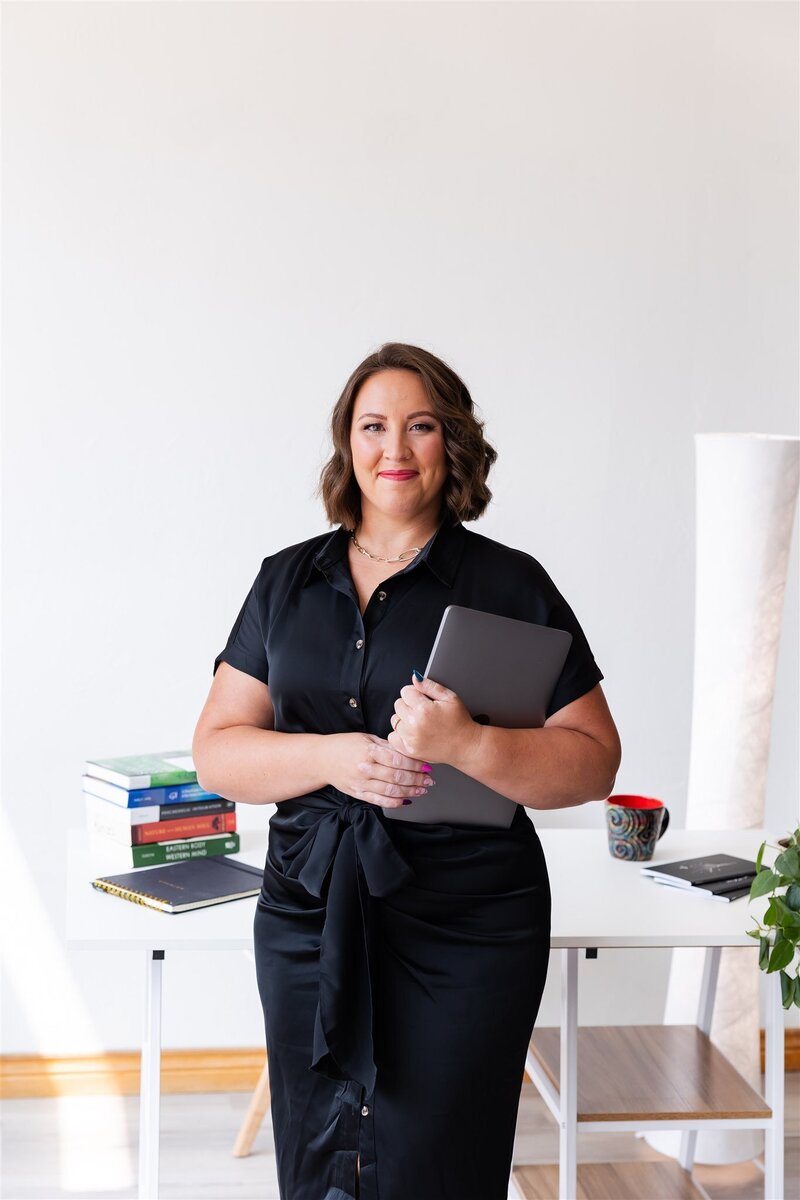 Kathryn Konicek holding her laptop in her Canon City therapy office