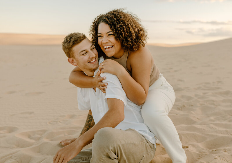 couple holding hands running through sand dune