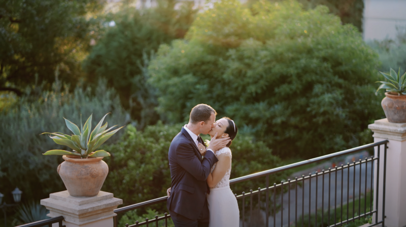 Romantic kiss between bride and groom on a terrace surrounded by lush greenery, captured during an elegant wedding in Italy — frame from a cinematic wedding video with natural storytelling style