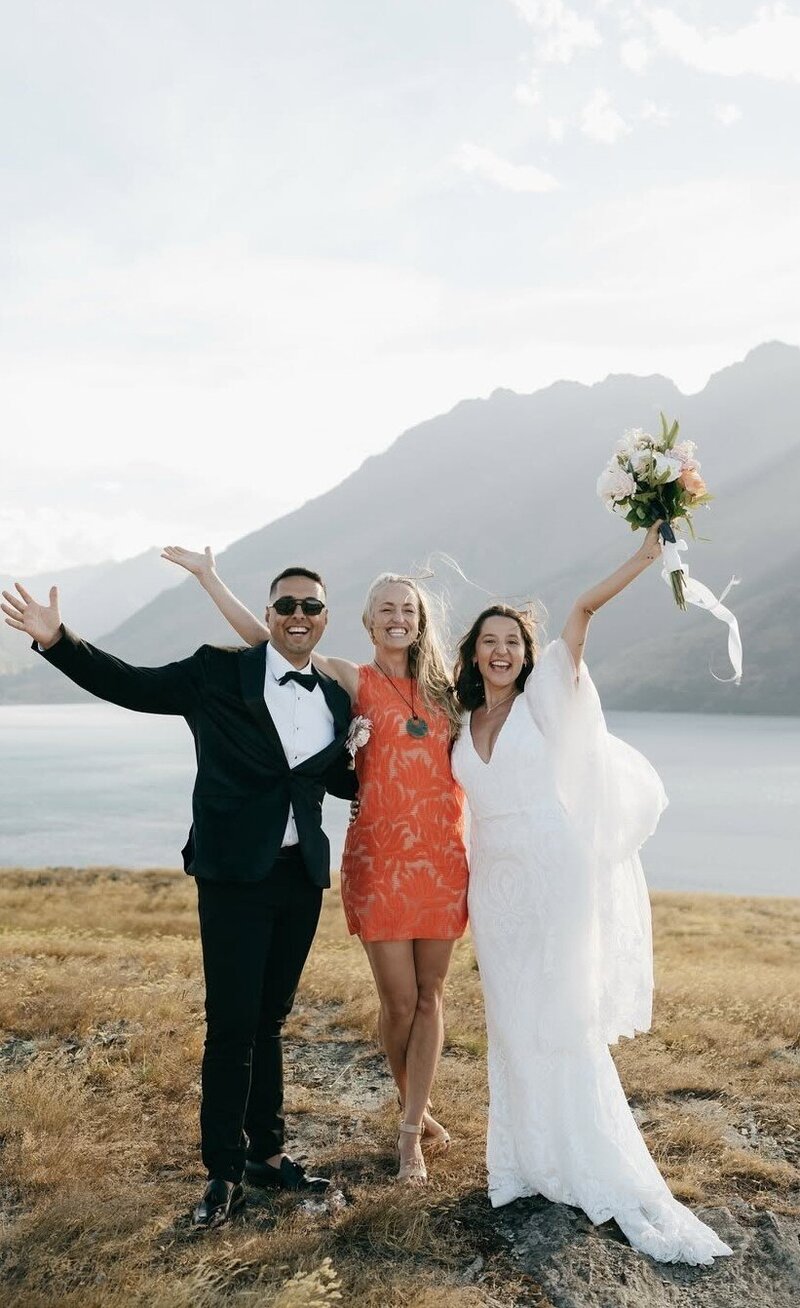 Bride and groom celebrating with officiant at scenic mountain lake wedding, outdoor ceremony with stunning natural backdrop.