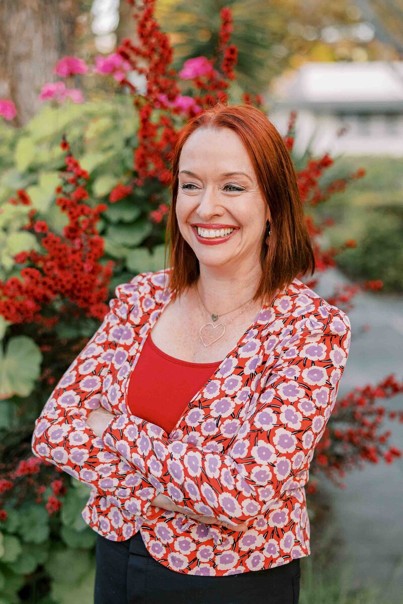 Donna Griffit headshot, redheaded woman wearing a red outfit and smiling into the distance