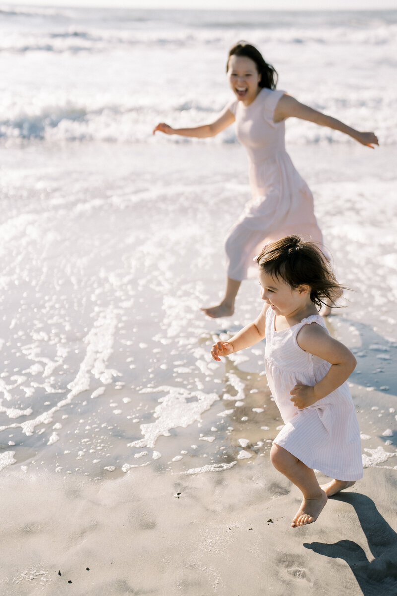 A mom and daughter running on the beach