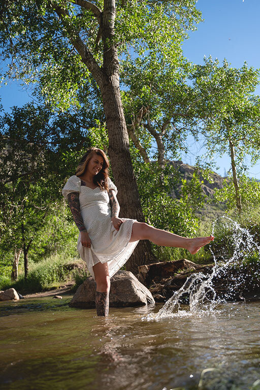 Portrait of a woman splashing in the river in a beautiful sundress.