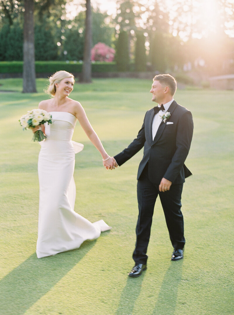 modern bride and groom walking in a golf course during golden hour