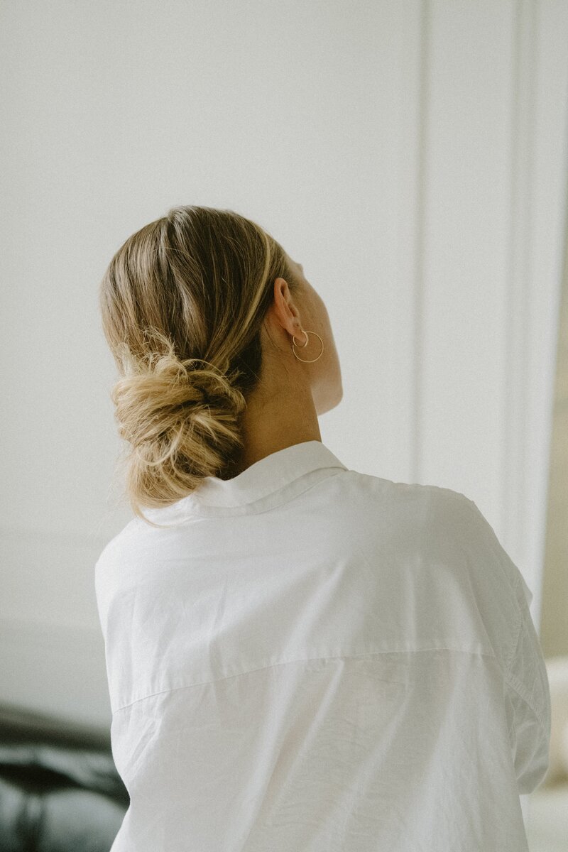 Blonde woman with low bun white shirt