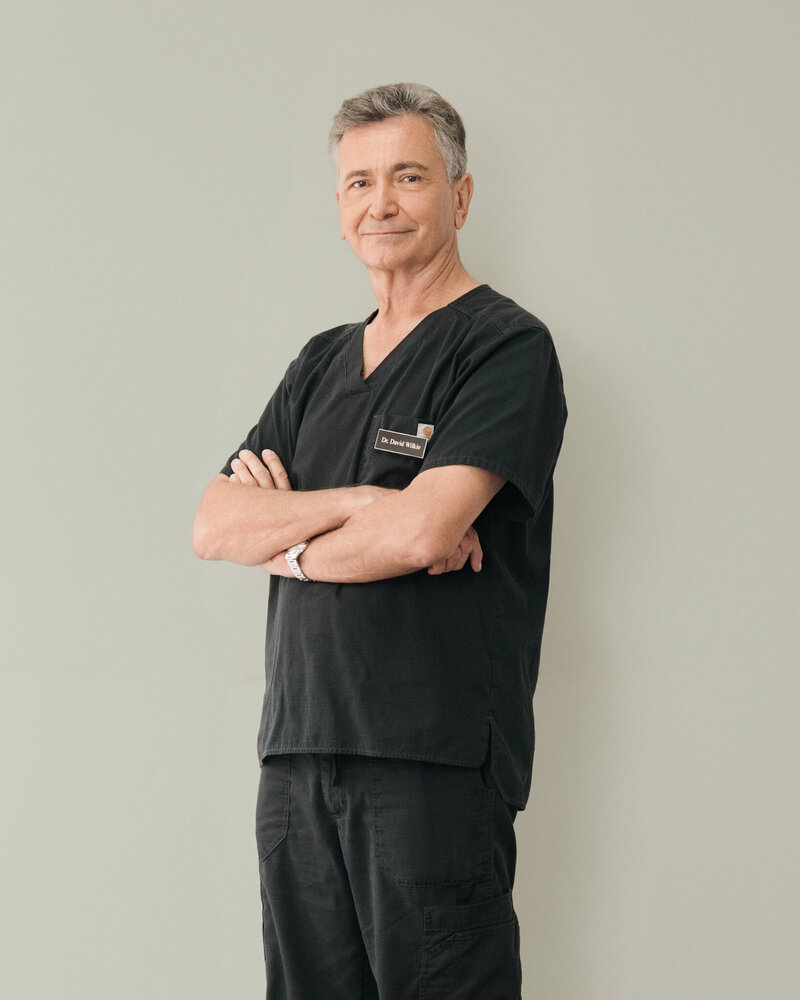 Dr Heather Dagenais leaning on a glass door with her arms crossed and smiling
