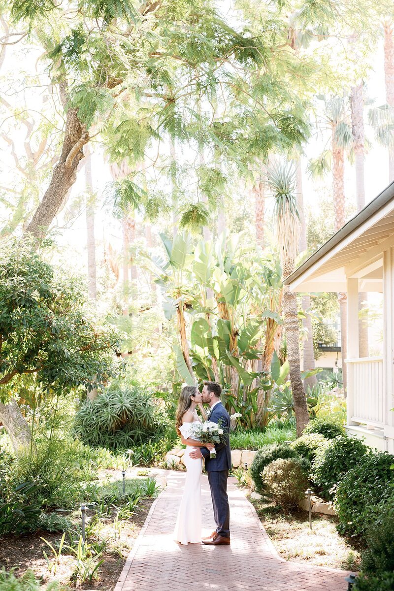 Bride and groom kiss on a tree lined path on their wedding day