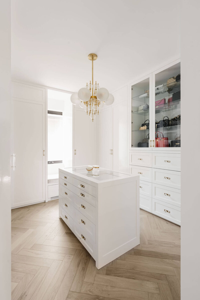 A high gloss walk in closet with a gold and crystal chandelier. 