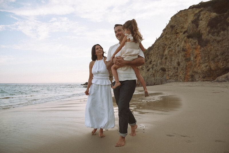Family walking along the shoreline in Laguna Beach during a candid golden hour photography session with Orange County family photographer Maria Alcantara.