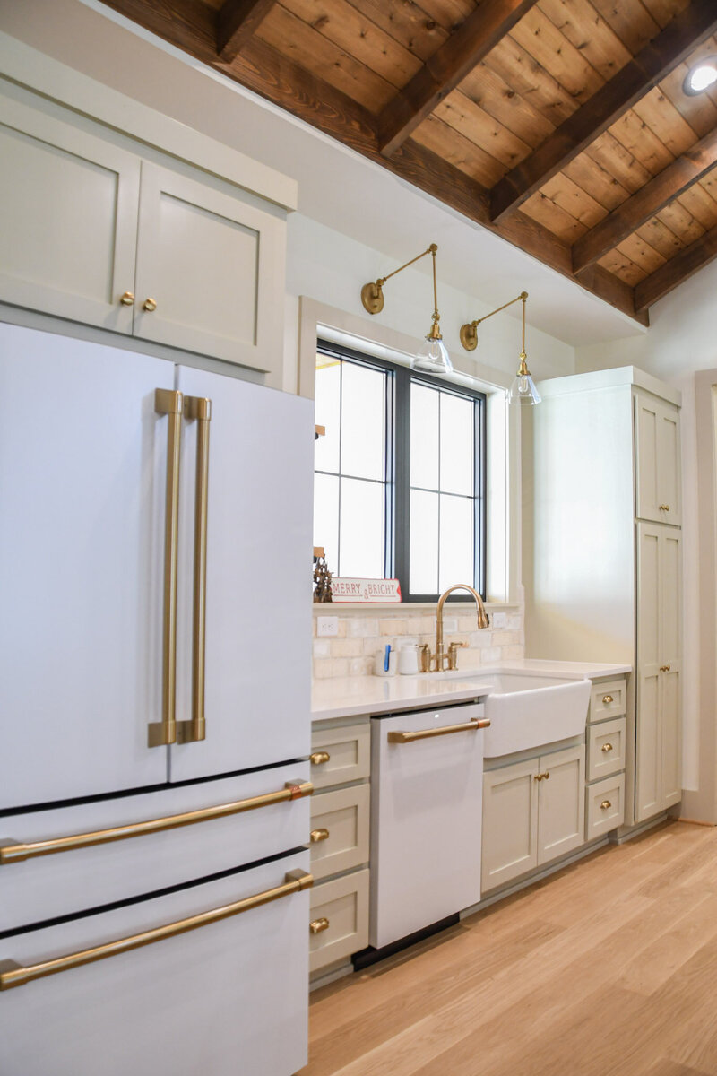 Brass kitchen fixtures, white refrigerator, custom cabinetry mushroom tone.