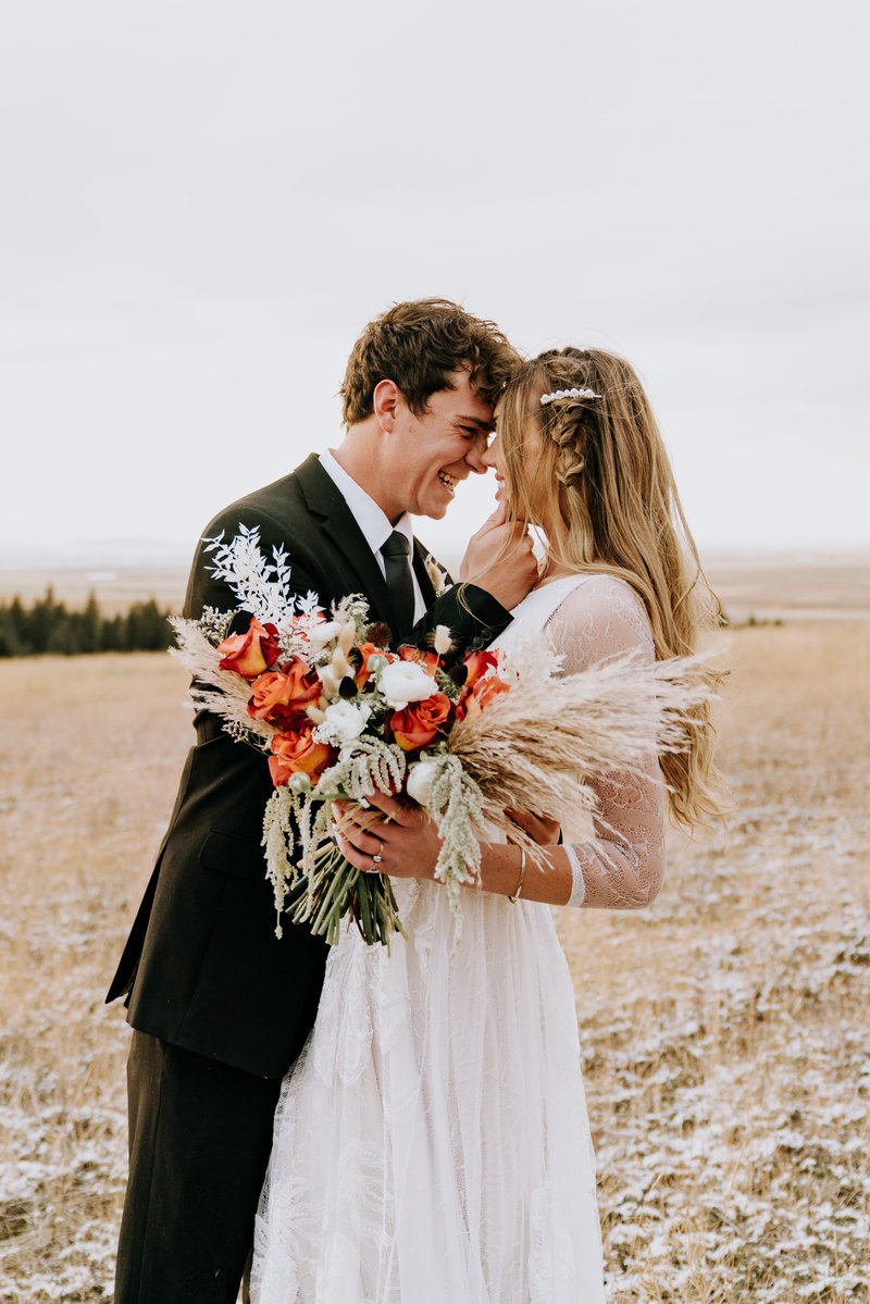 bride and groom holding a boho bouquet during winter intimate wedding ceremony in the midwest, photo by omaha wedding photographer, Kaitlyn Neeley