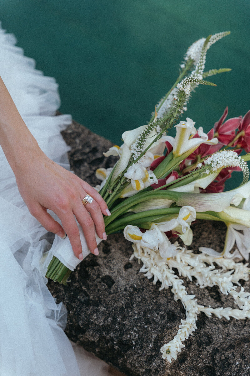 bride sitting by water with bouquet in miami wedding photos captured by elsie goodman, a destination and italy wedding photographer