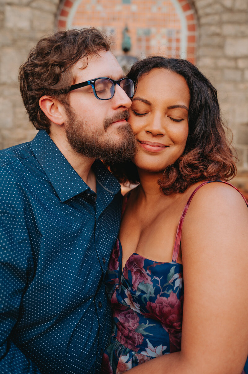 A couple puts their faces close while smiling with eyes closed