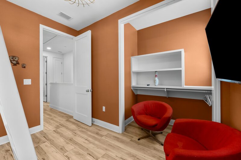 Groovy Shack bunk room featuring orange walls, mid-century chairs, and a built-in desk nook, perfect for kids or work-from-vacation days near Grayton Beach.