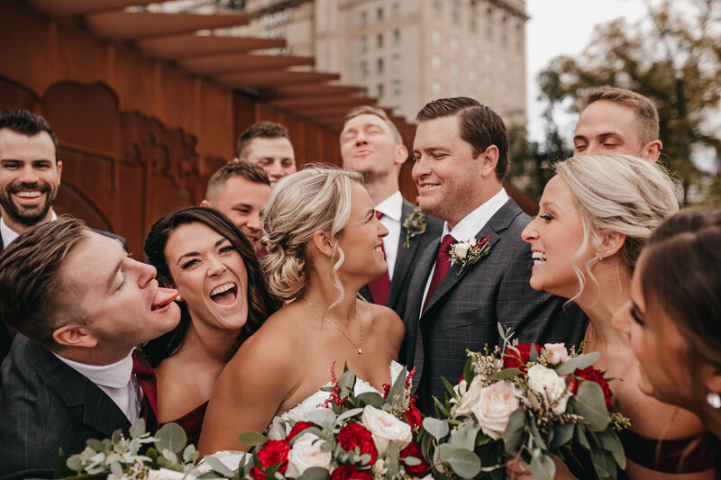 bride and groom surround by smiling bridal party