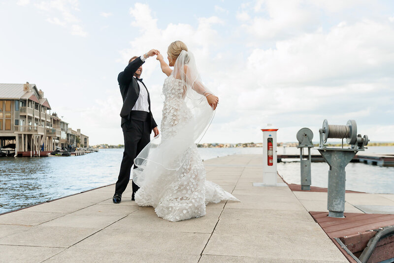 A bride and groom share a romantic dance on a dock by the water, symbolizing the elegance and charm of a waterfront wedding organized by Socially Significant Events.