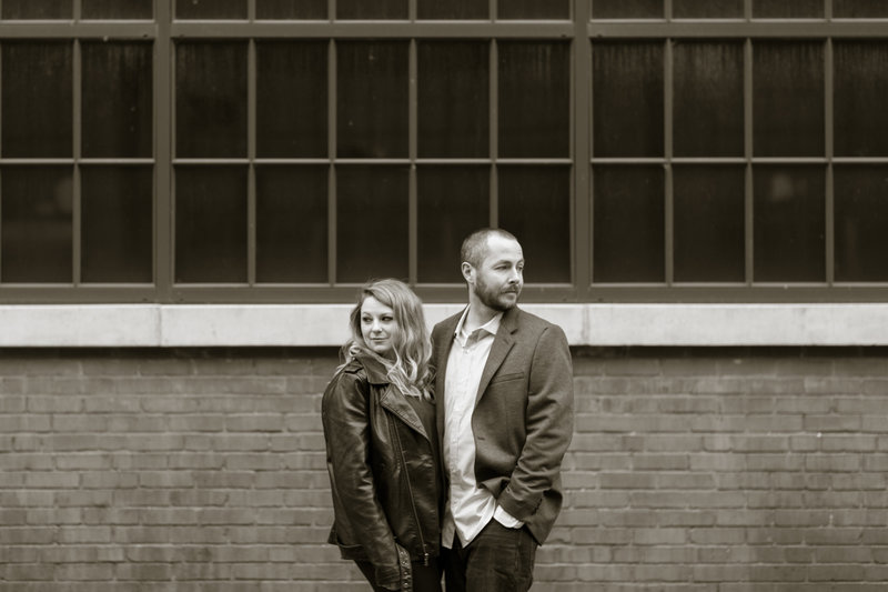 A black and white photo of an engaged couple striking a playfully serious pose at ArtsQuest in Allentown during their engagement session, blending creativity and humor against the venue’s unique industrial backdrop.