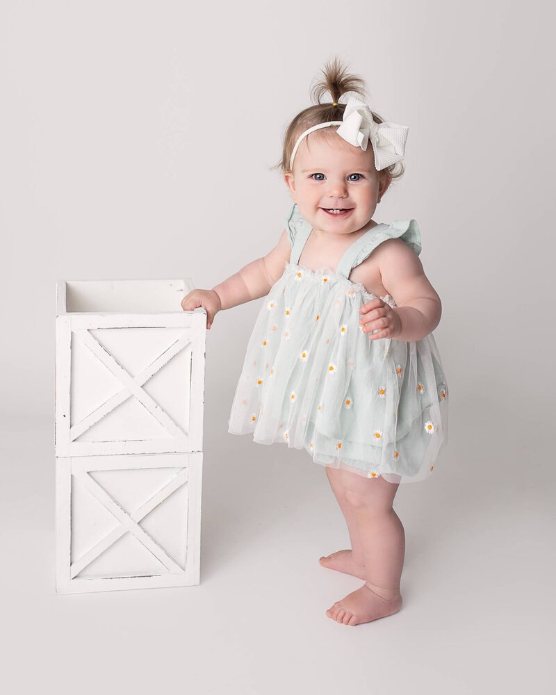 One year old baby milestone session with white blocks.