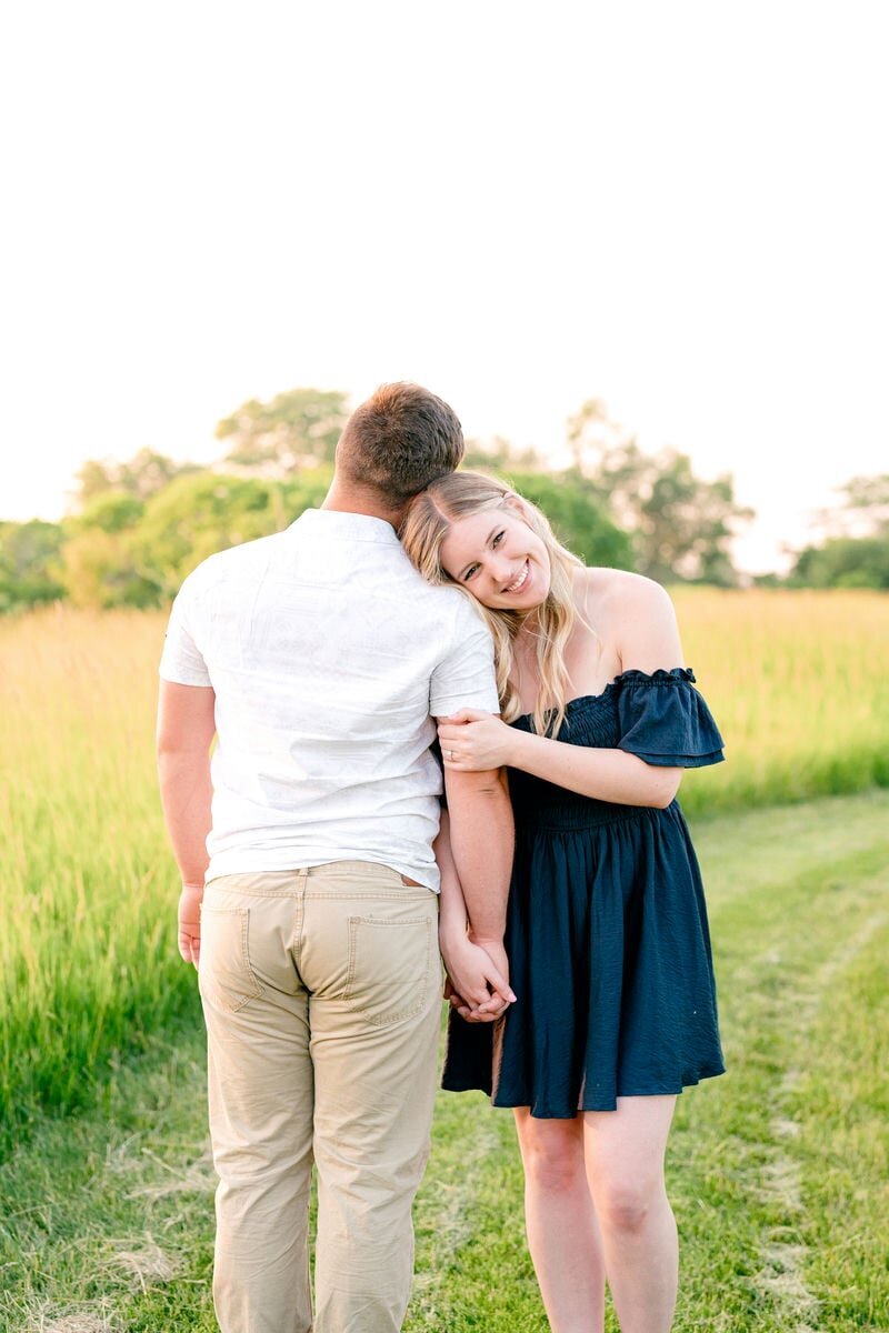 Engaged couple holding hands and smiling in a field