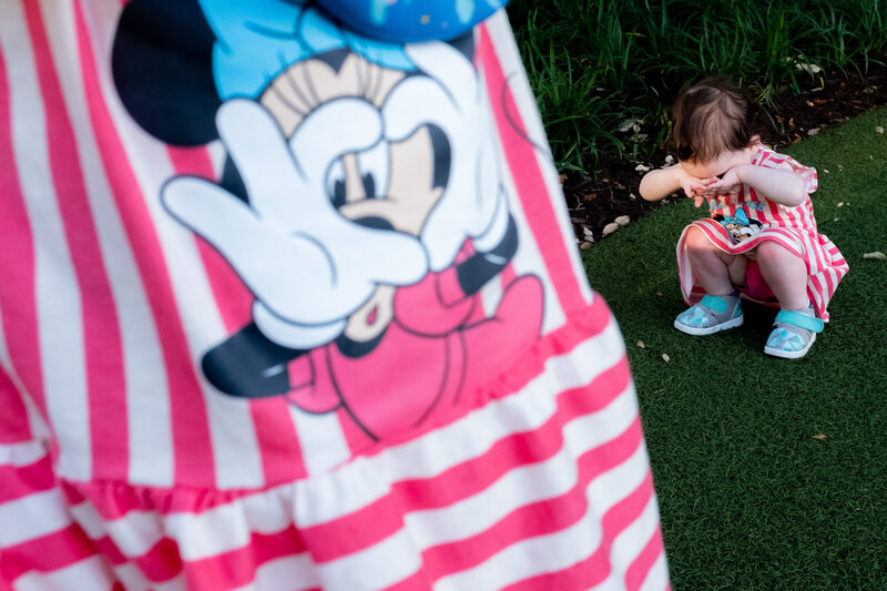 A little girl wearing a minnie mouse striped dress.