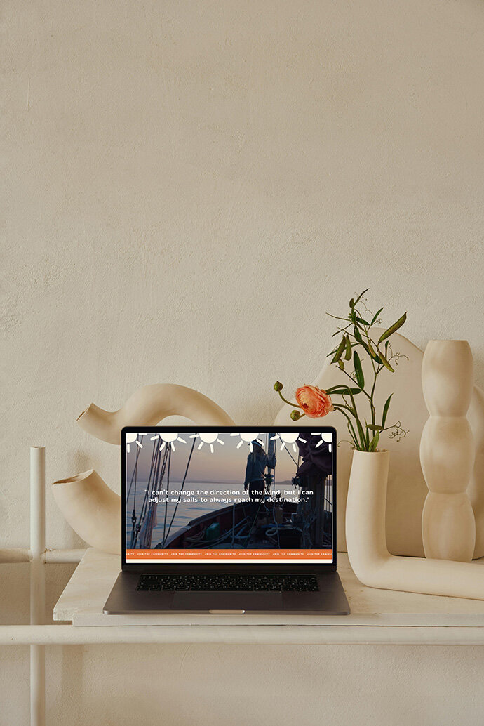 Laptop on a table in a coaching website's room, accompanied by two decorative vases.