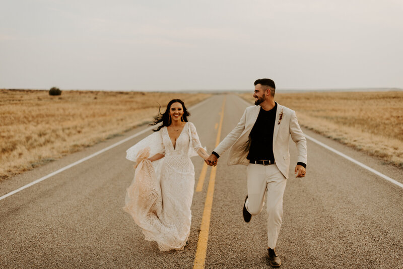 bride and groom running down highway
