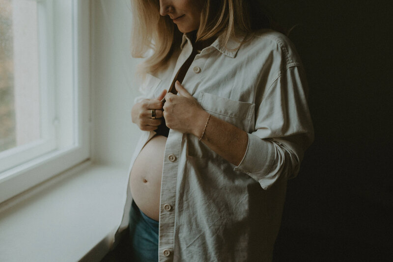 Pregnant woman standing by the window at her home in Helsinki