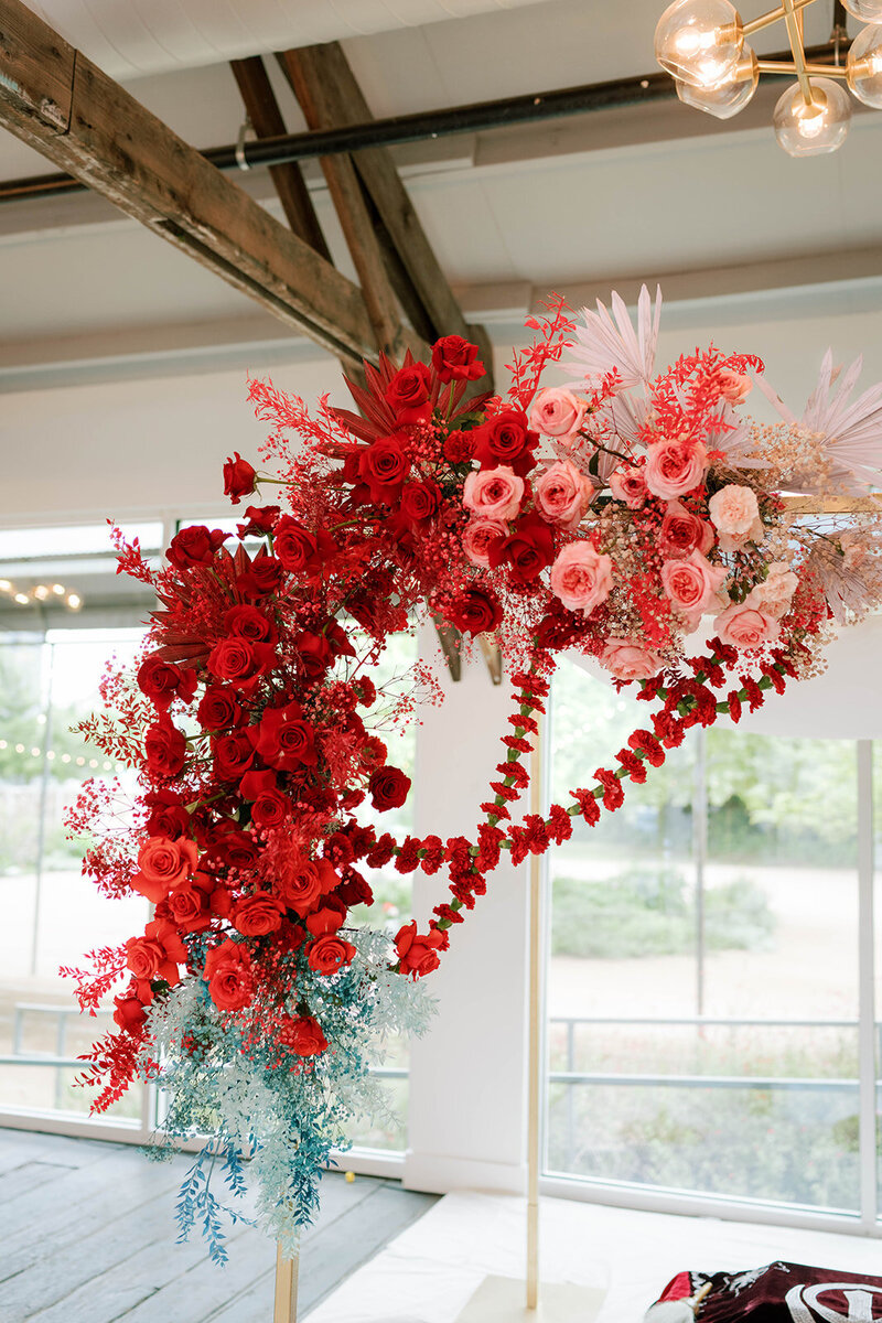 Romantic event floral installation with red and blush roses, styled for an unforgettable wedding or upscale brand launch.