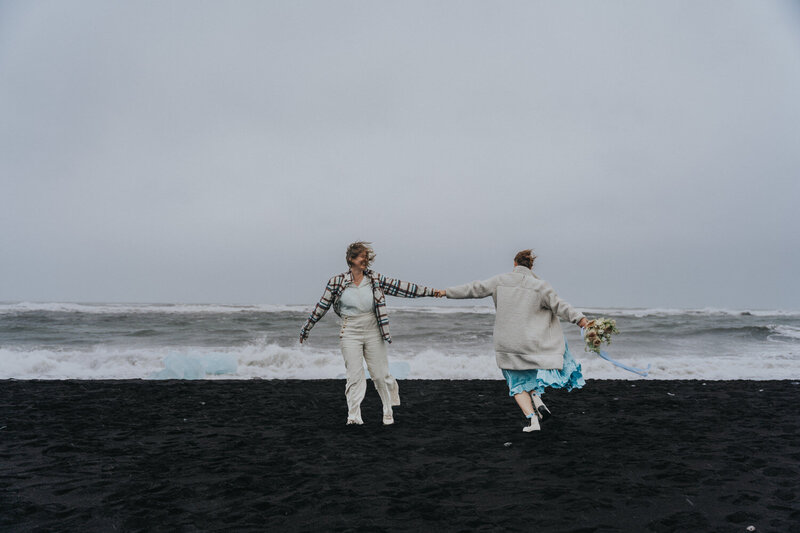 Wives spin around hand in hand on the Black Sand Beach of Iceland